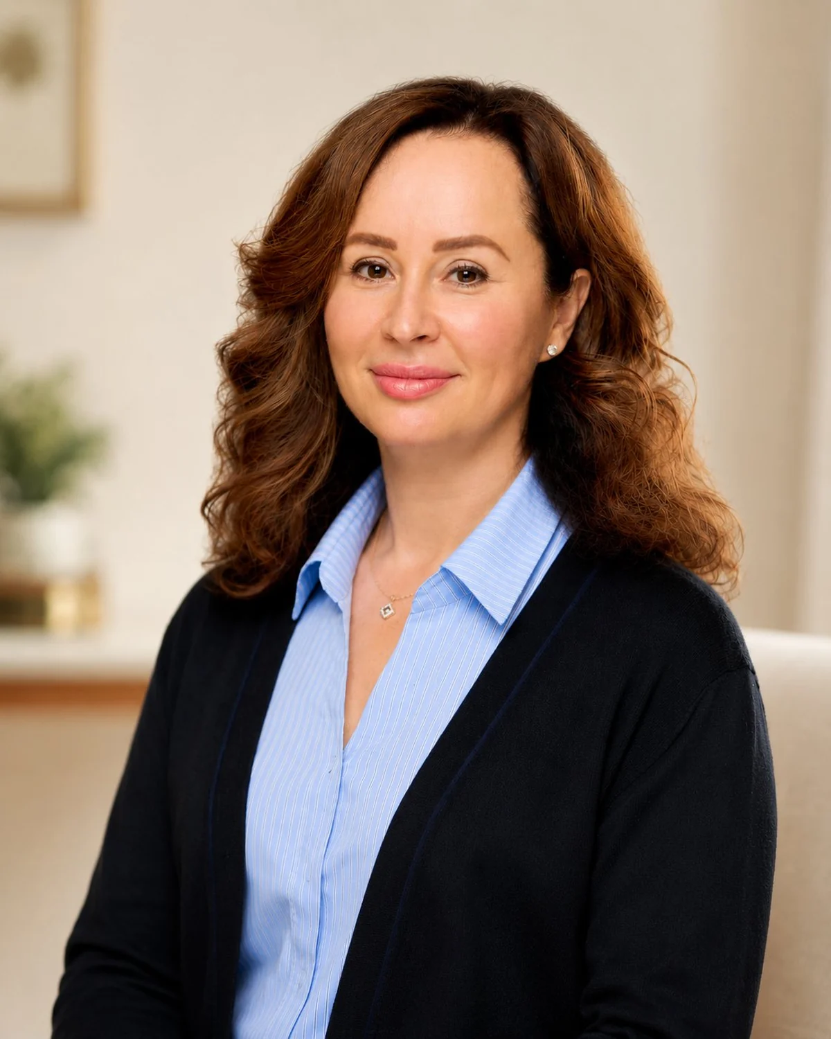 Dr. Alla Patish-Preobrazhenskaya, professional fiduciary, seated indoors in a dark cardigan over a light blue shirt, with a calm, approachable expression.
